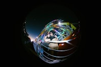 a couple standing in front of a ferris wheel at night