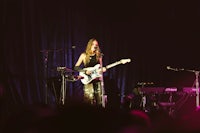 a woman playing a guitar on stage in front of a microphone