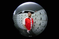 a man in a red jacket standing in front of a locker