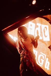 a man holding a microphone in front of a neon sign