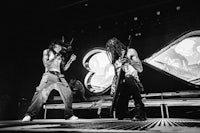 two people playing guitar on stage in black and white