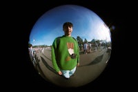 a man in a green sweater standing in front of a mirror