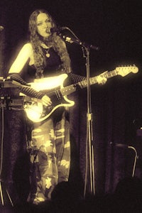 a woman playing a guitar in front of a microphone