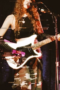 a woman playing an electric guitar in front of a microphone