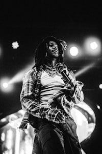 a black and white photo of a man with dreadlocks on stage