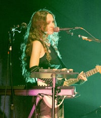 a woman playing a guitar in front of a microphone