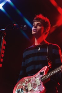 a young man playing a guitar in front of a microphone