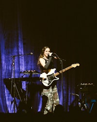 a woman singing on stage with a guitar