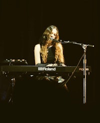 a woman playing a keyboard in front of a microphone