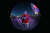 a person standing in front of a ferris wheel at night