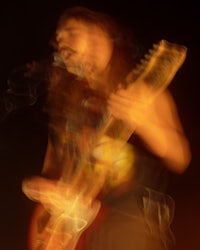 a blurry image of a man playing an electric guitar